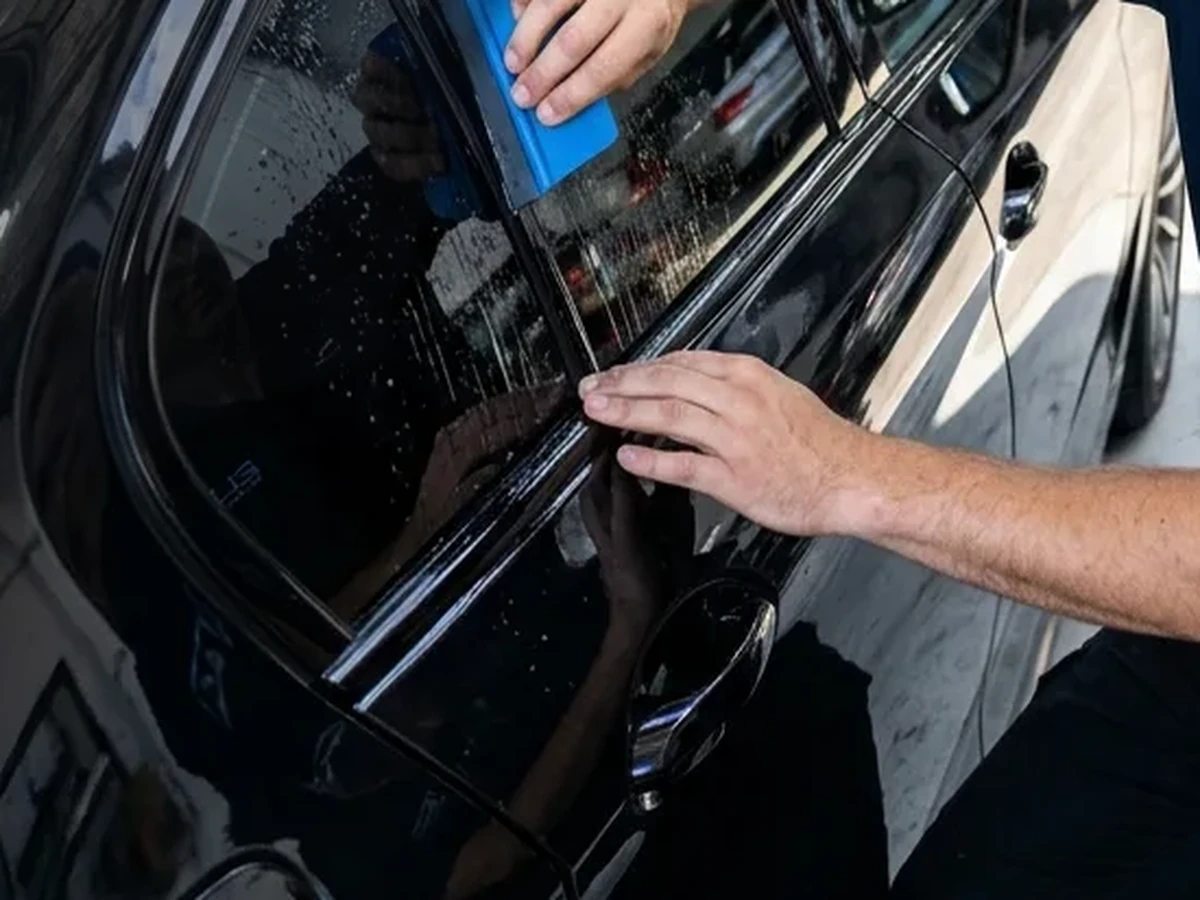 Manos aplicando lámina solar sobre la ventanilla